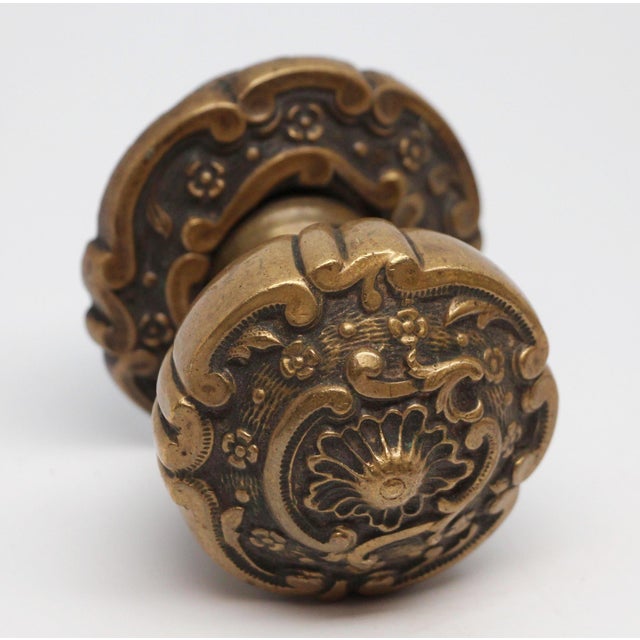 Odd shaped decorative knob made of brass in an antique finish. It includes a matching rosette. The manufacturer and date...