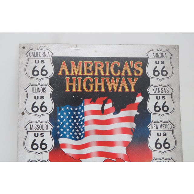 This stylish Route 66 sign features two brightly colored vintage style cars, one red and one yellow, beneath an American...