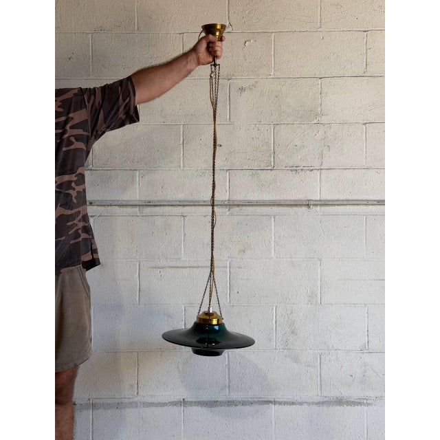 This elegant pendant lamp features a rich green glass shade paired with polished brass hardware and a hanging chain. The...