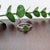 A rare tsavorite (garnet) sits in a vivid grass green at the heart of this solid 14K white gold ring, flanked by six...