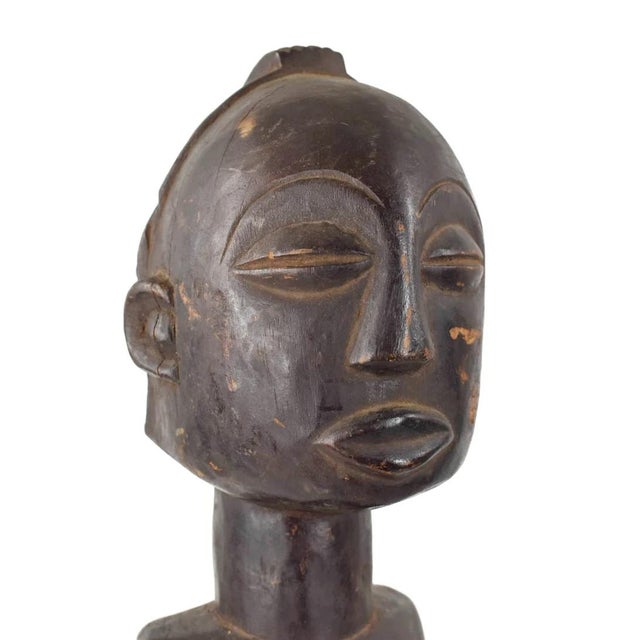 The Luba female figure is crafted as a veneration of feminine beauty and motherhood. Crafted from wood, the Luba female...