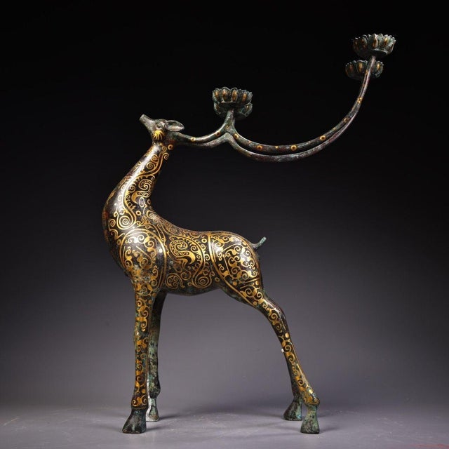 This is an ornate cast bronze candelabra in the form of a standing deer, featuring extensive gold inlay (gilt bronze)...