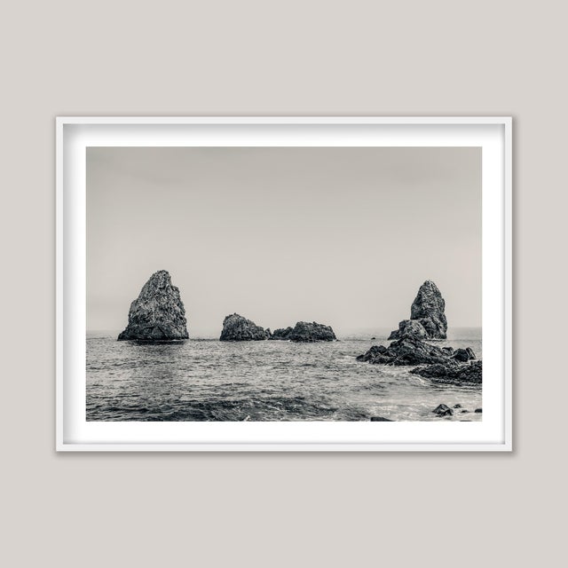 A sepia-toned black-and-white photograph of the Cyclopean Islands, Sicily, Italy. This striking cluster of volcanic rocks,...