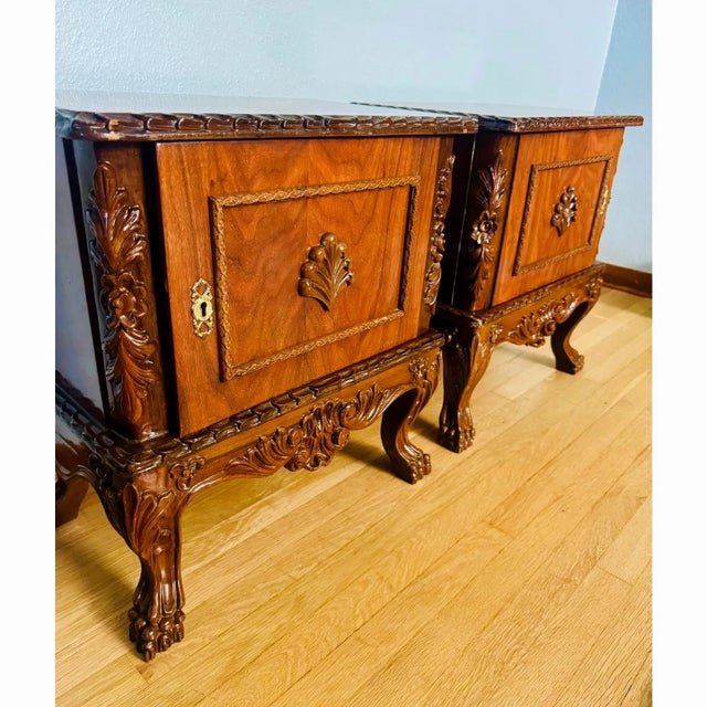 A handsome pair of carved wood nightstands featuring figured veneer door panels, cabriole legs, and substantial carved...