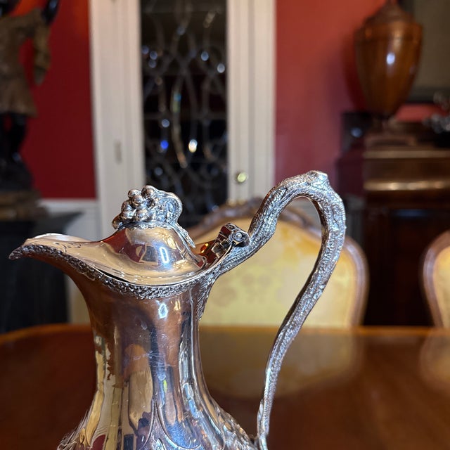 Hallmarked London, 1788 Claret Wine Serving Ewer. Baluster-form, the body chased with a band of grape clusters and vines,...