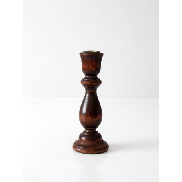A vintage turned wood candle holder with a dark brown finish, brass candle insert, and a classic baluster silhouette. the...