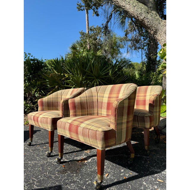 Charming set of four vintage game table chairs featuring a classic warm-toned plaid upholstery in shades of burgundy, tan,...