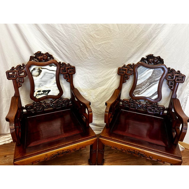 A striking pair of vintage Chinese armchairs, hand carved in solid rosewood with exceptional detail throughout. Each chair...