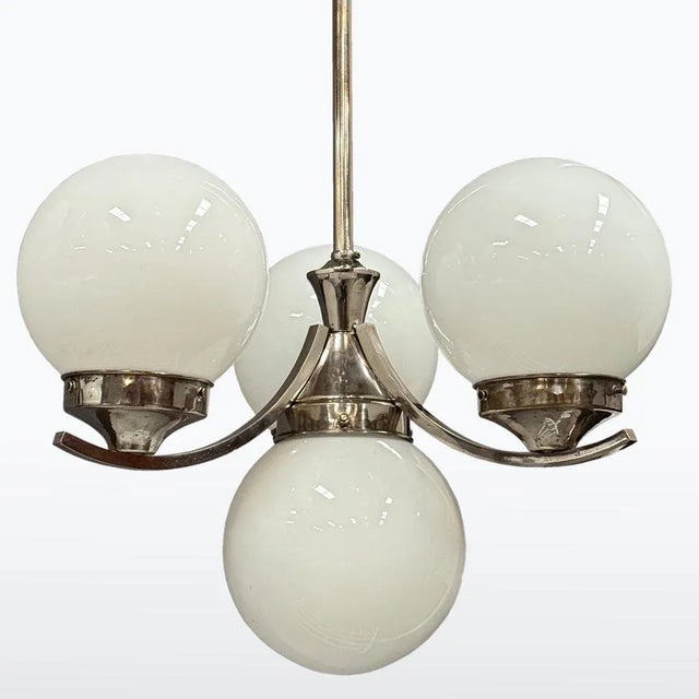 Elegant chrome chandelier from the Art Deco period, featuring four spherical opaline glass shades. Its clean lines and...