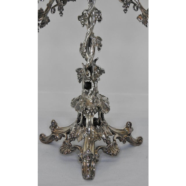 This is a stunning silver plate epergne with four removable arms and an engraved glass bowl. Three ornate feet lead up to...