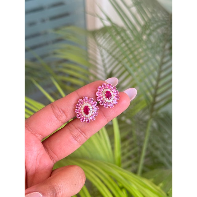 These elegant 6.55 carat oval ruby, pink sapphire, and diamond cluster stud earrings are crafted in 14K yellow gold. The...