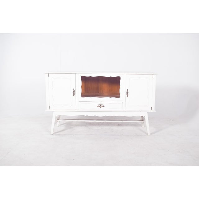 Sideboard painted white. The sideboard is marked by sinuous lines in the door cut-outs and the central niche, as well as...