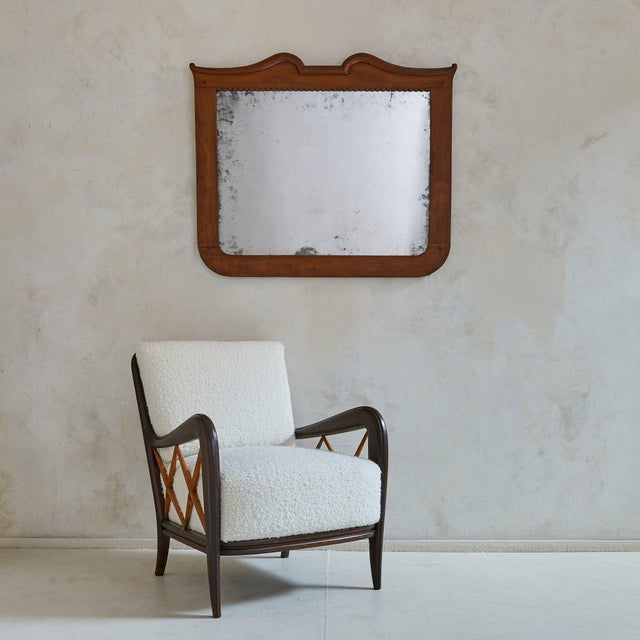 An Italian neoclassical wall mirror from the 19th century, carved in warm cherry wood. The crest unfolds in a gentle arch...