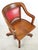 Early 20th century swivel office chair made of solid oak with a studded red vinyl backrest. It features an adjustable...