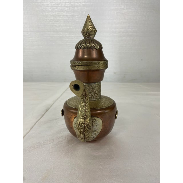 Vintage middle eastern copper and brass tea or coffee pot with chain and lid.