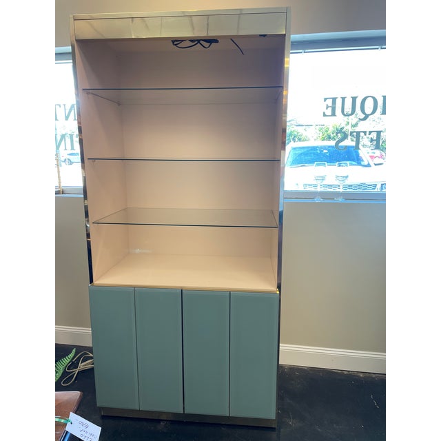 A striking vintage attributed to Ello display cabinet featuring a brushed gold-toned frame with glossy blue lacquered...