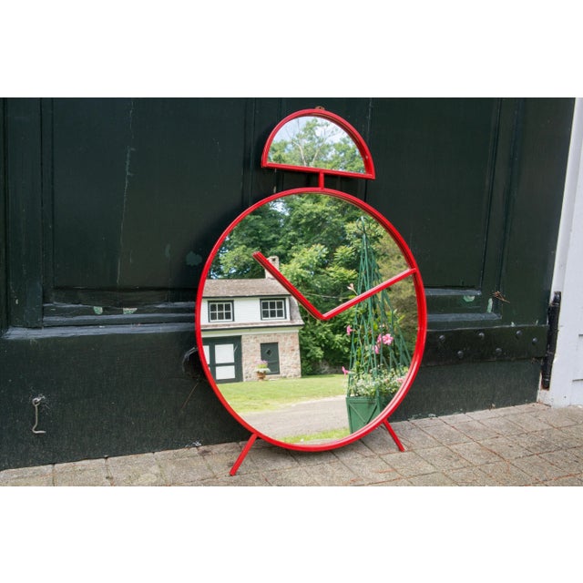 A very unusual and whimsical wall mirror in the shape of an alarm clock red lacquered metal. Made in Italy, marked Pilm.