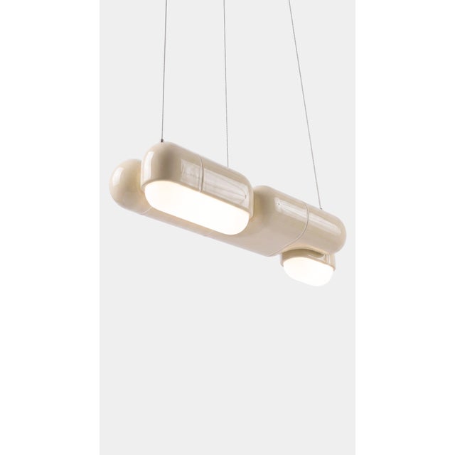 A linear pendant made for the table everyone gathers around. The curved-tile module repeats along its length, so light...