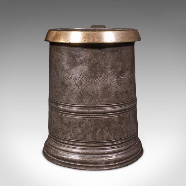 This is an antique public house tankard. An English pewter and brass quart jug, dating to the late Victorian period, circa...