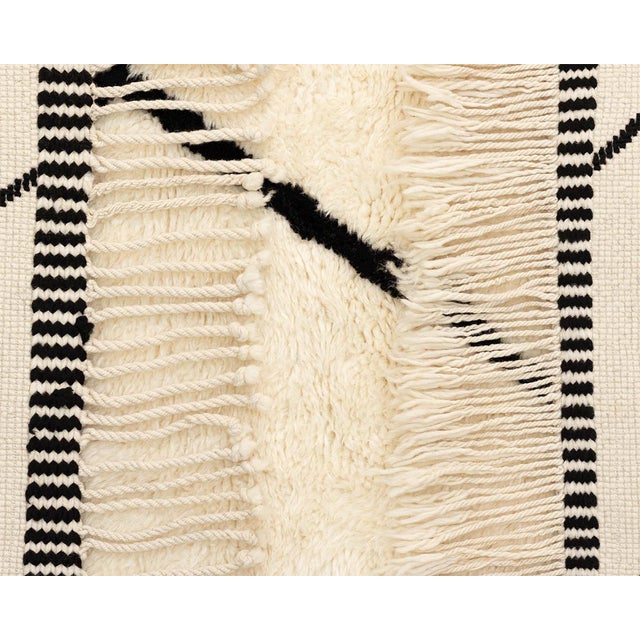 Sophisticated hand-knotted wool rug with a striking Midnight Black abstract pattern on an Ivory base, offering a...