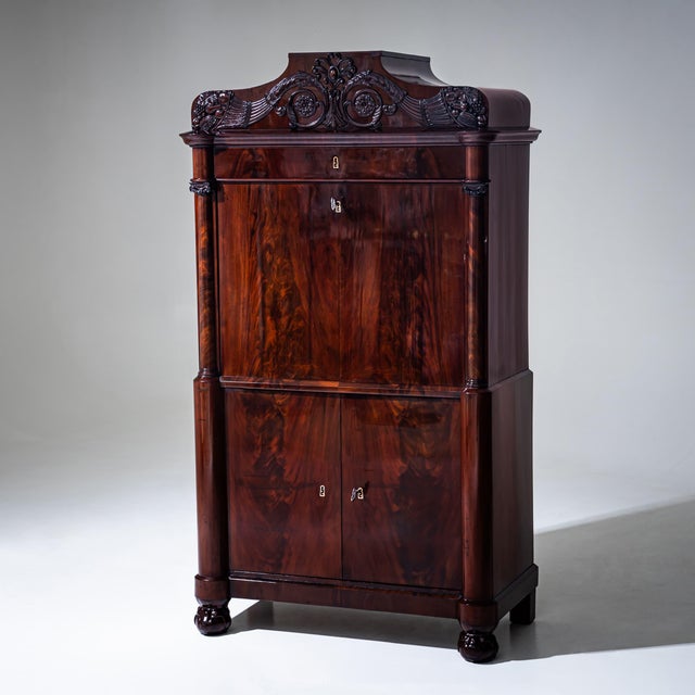 Louis Philippe secretary desk veneered in mahogany, featuring a flat writing flap, two-door lower cabinet, and a top...