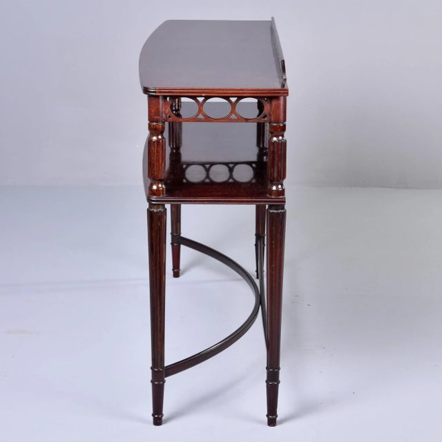 Found in England, this slender two tier mahogany console dates from the 1930s. Table top has a low back panel and an apron...