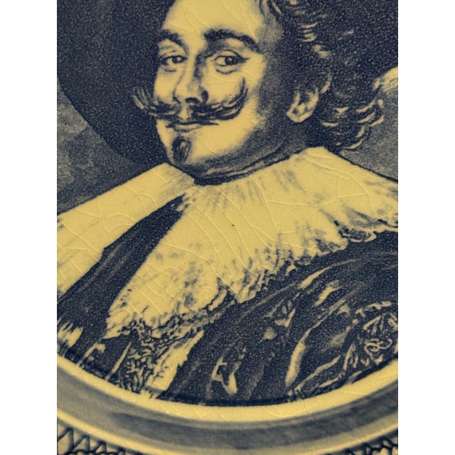 A nice vintage delftware tin-glazed earthenware decorative plate featuring a central portrait of De Lachende Cavalier,...