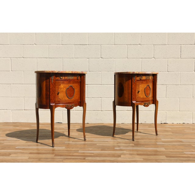 Beautiful pair of French Louis XV-style nightstands / end tables, circa 1940s. Crafted with richly figured wood and...