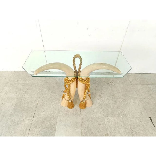 Striking wooden faux tusk console table with a beveled glass top. Very elegant hollywood regency piece. Beautifully...