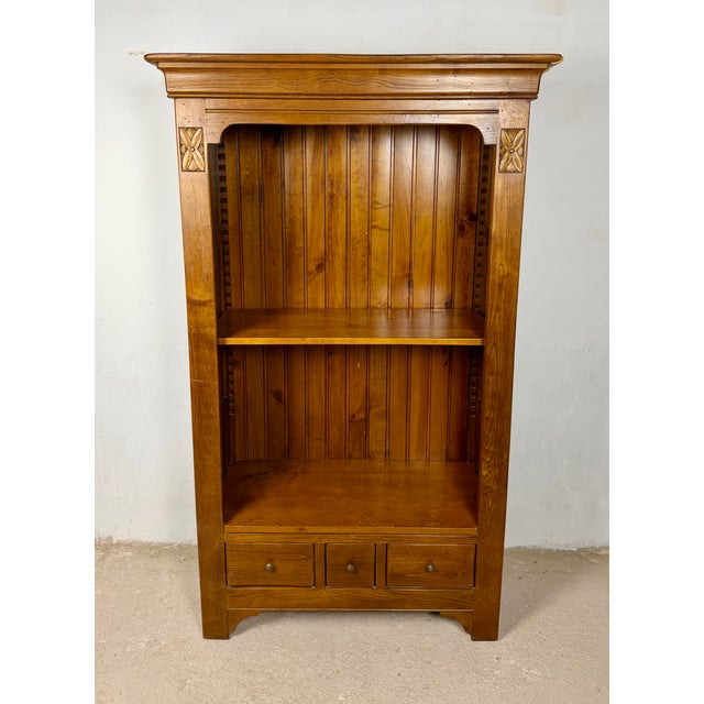 Spanish oak bookcase featuring a tall and elegant structure with a molded cornice and subtle carved details. The open...