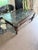 A showpiece coffee table featuring a heavy dark wood frame with ornately carved legs and a glass top that reveals...