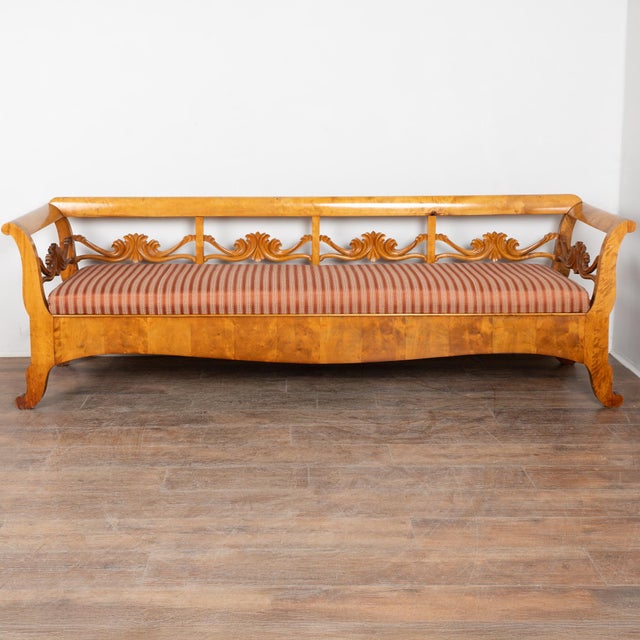 19th century Swedish Karl Johan style bench crafted in glowing birch. The bench features slightly outward curving arms...