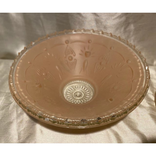 A pair of Art Deco glass ceiling shades in a pale blush pink/peach color flashed on the interior of the shades. The shades...