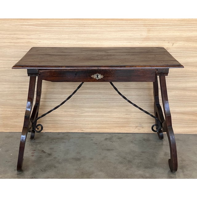 A Spanish walnut side table with single drawer, scalloped apron, carved legs and iron side stretcher from the late 19th...