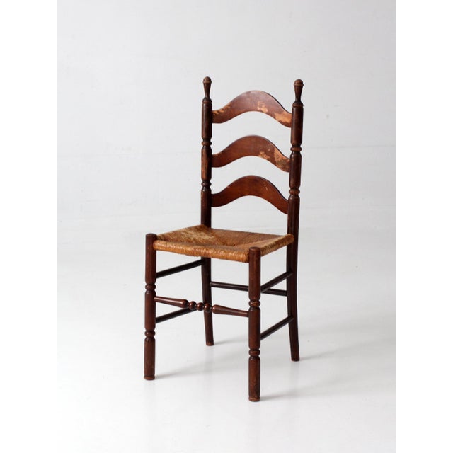 A vintage Tell City Chair Company ladder-back chair with a beautifully aged dark brown finish and woven rush seat. Three...