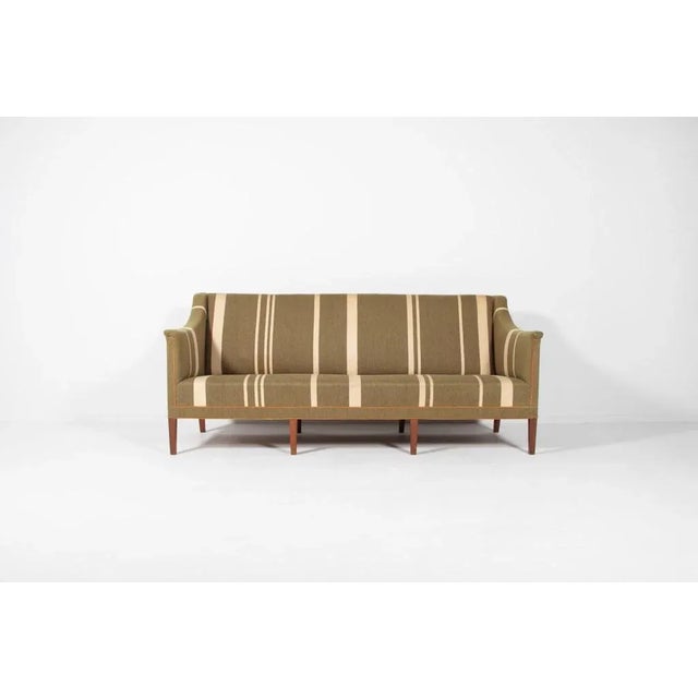 Danish Modern sofa by Kaare Klint, model 6092. The sofa has a mahogany frame on eight tapered legs, upholstered in striped...