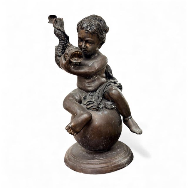 This delightful bronze sculpture captures a chubby, mythological Putto (a cherub-like child figure) seated playfully atop...