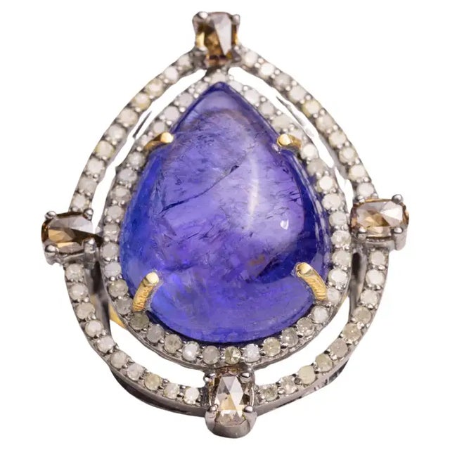 A lovely, large pear-shaped cabochon Tanzanite dome cocktail ring bordered with two rows of round, brilliant cut diamonds...