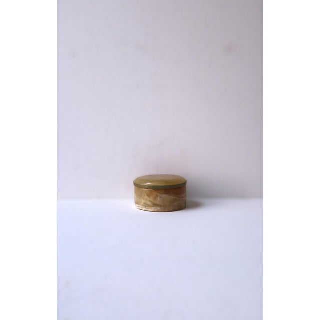 A small neutral onyx marble round jewelry or trinket box, in the Modern style, circa 20th century. Box is round with...