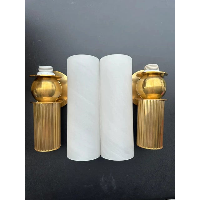 The Corbett Lighting Ronda wall sconces feature a fluted vintage brass body and matte cloud glass shade inspired by...
