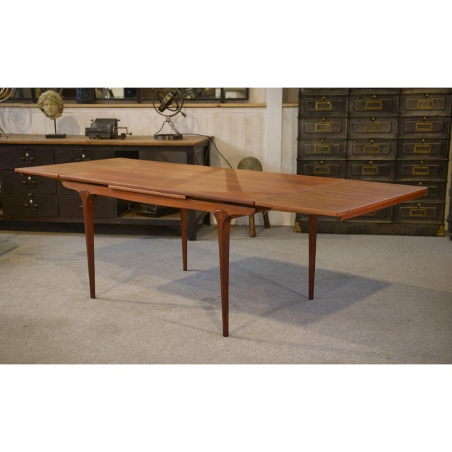 A Danish teak dining table, typical of 1960s Scandinavian design, with clean, balanced lines. The rectangular top features...