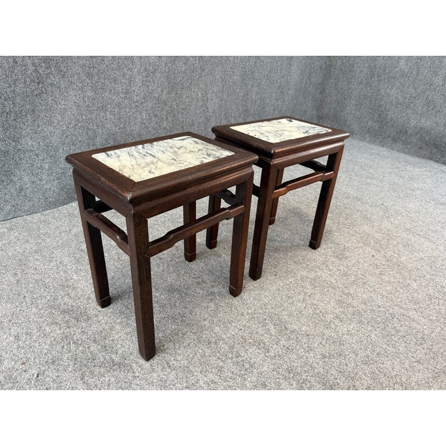 These versatile pieces feature dark wood frames with inset marble tops showcasing natural veining. Their compact size...