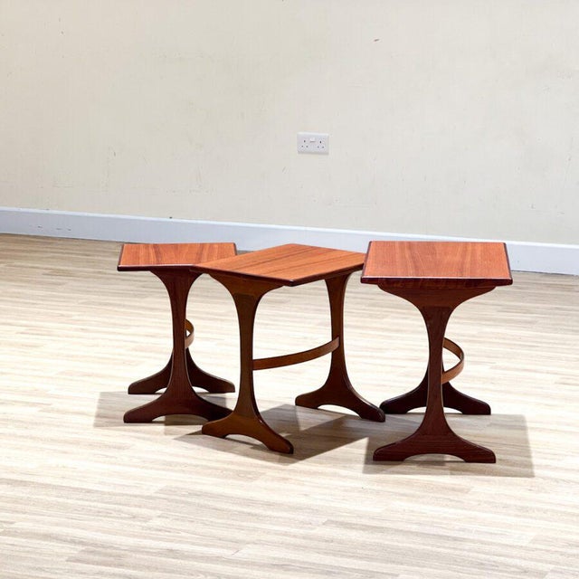 The exquisite set of three nesting tables is a testament to the timeless craftsmanship of the renowned British furniture...