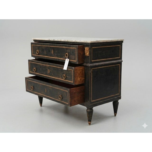 An elegant French Louis XVI style three-drawer commode (chest of drawers) featuring a striking ebonized black. The chest...