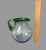 This Mexican hand-blown art glass pitcher is a true masterpiece. The attached handle and festive green rim add an element...