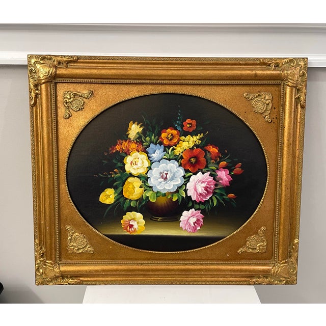 Classic mid-20th-century floral still life presented in an ornate gilt wood frame with an oval cartouche opening. The...
