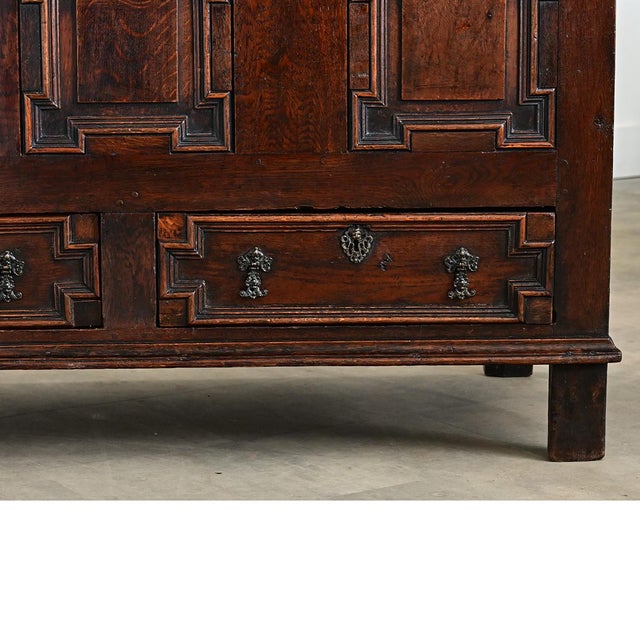 An English, solid oak mule chest from the mid-18th century or earlier, this heavy storage trunk has a paneled exterior...