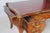 A grand French bureau plat combining warm parquetry, an oxblood tooled-leather writing surface, five drawers, and...