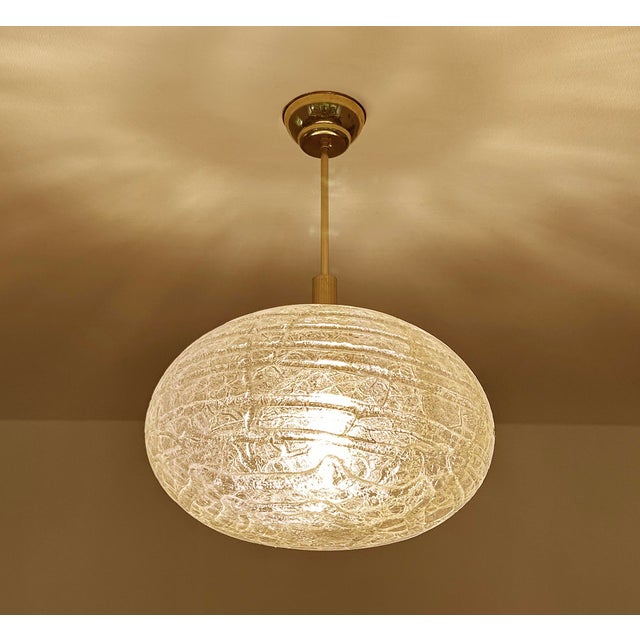 Vintage Doria Glass pendant light featuring a cocoon shade with signature "lava flow" patches, polished brass cover and...