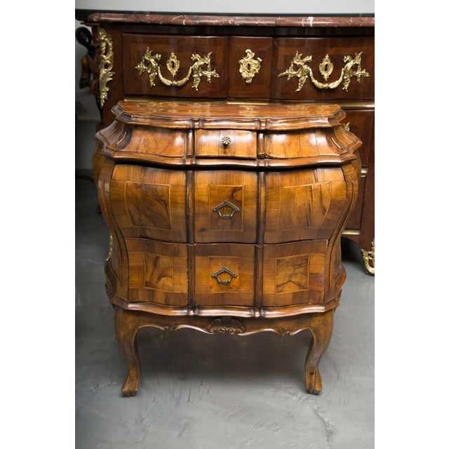 This is an exceptionally fine pair of Italian Rococo style walnut bombe commodes. The shaped top is crossbanded in walnut...